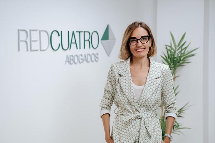 PILAR VALLADARES SALMERÓN Abogada posando frente a pared del logo de RedCuatro Abogados